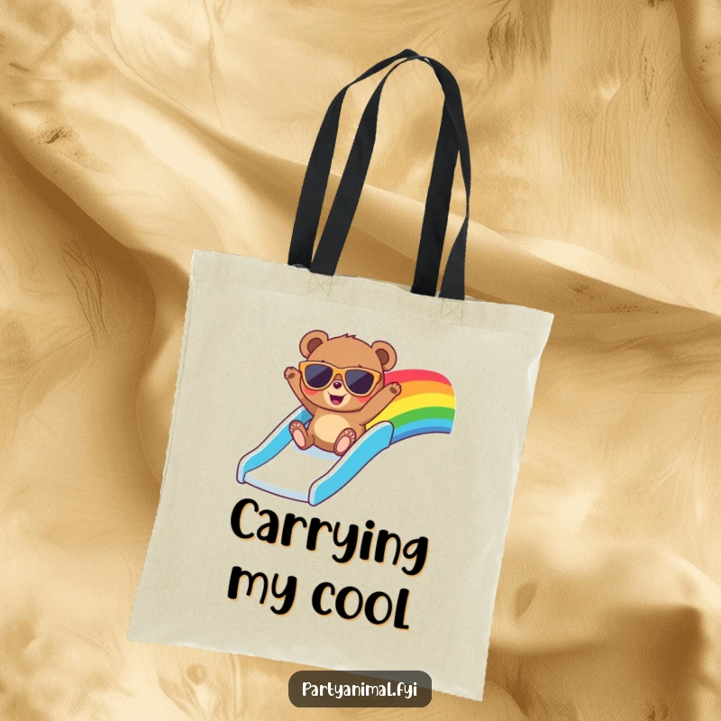 Funny tote bag featuring a bear in oversized sunglasses, gleefully sliding down a colorful rainbow, perfect for carrying fun finds.